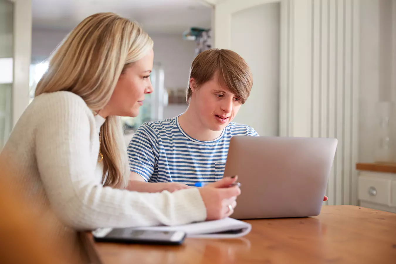 A disabled man and his support worker in the table with a laptop