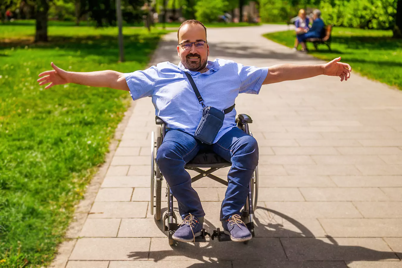 A disabled man sitting in his wheelchair opening his arms for a hug